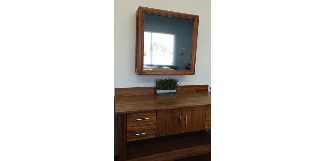 medium wood vanity and mirrored cabinet